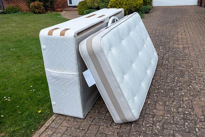 two workers carrying a large mattress for removal