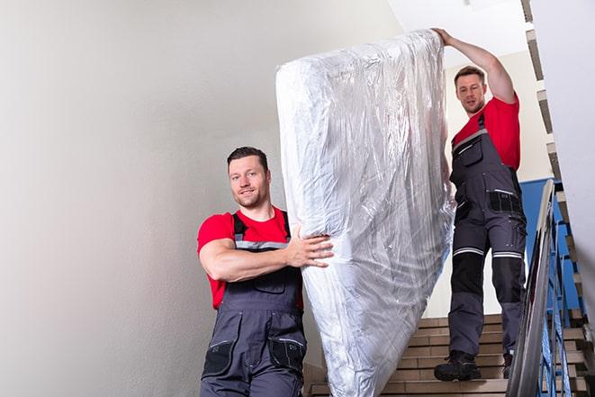 team carrying a large box spring out of a bedroom in Garrison